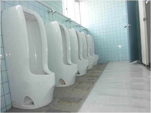 青いタイルの壁に男性用便器が5台並んでいる男子トイレの写真
