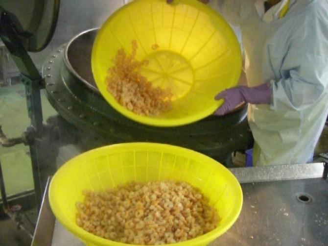 大きな釜で茹でたえぴを黄色のザルで取り出している写真