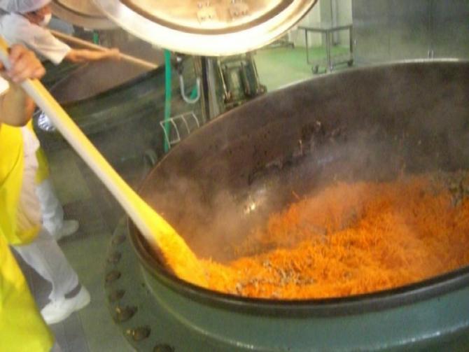 大きな釜に入れた材料を大きな木べらでかき混ぜている写真