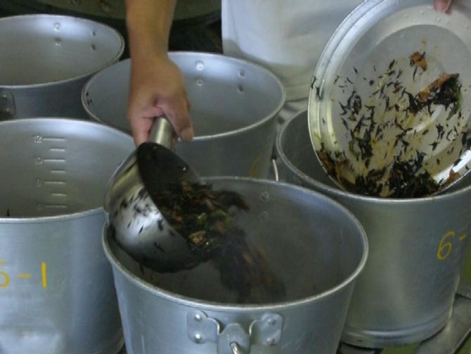 出来上がったひじきの三色炒めを、小鍋で食缶に移し替えている写真