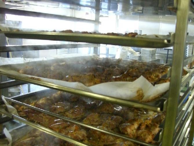 縦長の大きなラックに積まれている、天板に並べた鶏肉がきつね色に焼きあがった写真