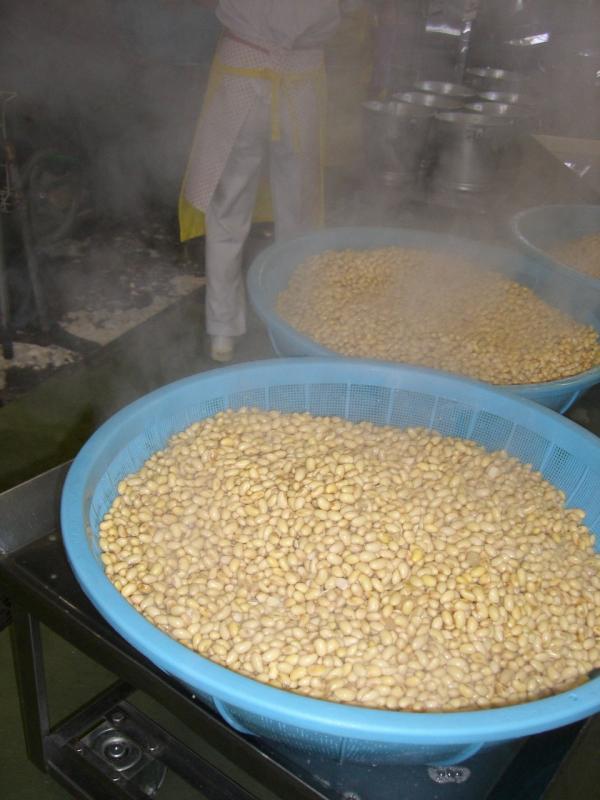 湯がいた大豆が大きな水色のザルに入って蒸気が出ている写真
