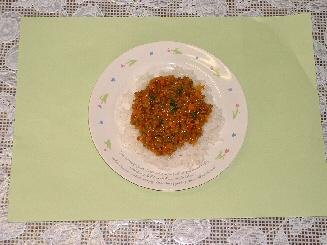 白い器にご飯が敷かれ、その上に豚ひき肉や野菜などで調理され完成し盛りつけられたドライカレーの写真