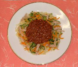 白い皿に、麺の上にハムや野菜などの具材、その上に肉みそがのっている完成したジャージャーめんの写真