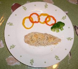 白い皿の上に黄色とオレンジのパプリカを輪切りにしたものを2つずつ交差させて並べて右側にブロッコリー2個を置き、その下に調理されたささみのチーズ焼きを盛り付けた写真