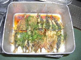 クラスごとの食缶の中に、人数分のたれと青のりをまぶした完成したいわしが並んでいる写真