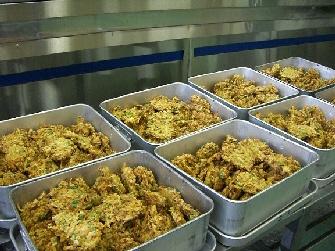人数分のかき揚げが8つの食缶に並べ入れられている写真