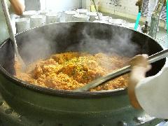 炊き上がったチキンライスを木べらで左右からよく混ぜている写真