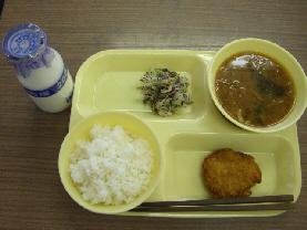 給食トレーの上にごはん、どさんこ汁、れんこんサンドフライ、ゆかりあえが盛り付けられ、左横に牛乳瓶が置いてある写真