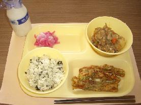 給食トレーの上に、わかめごはん、肉じゃが、ちくわの磯辺揚げ、かぶの甘酢づけが乗せてあり、左上に牛乳瓶が置いてある写真