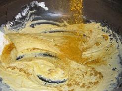 大きな釜で炒めた小麦粉に、カレー粉などを上から投入している写真
