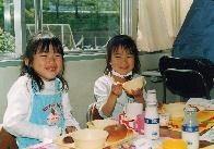給食を笑顔で美味しそうに食べている2人の女児の写真