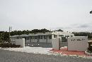 広い敷地内に建っている、白壁で一階建てのながくてエコハウスの建物外観の写真