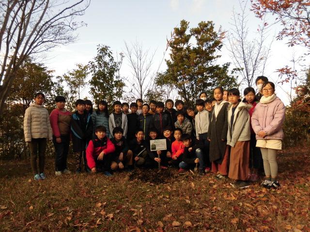 被爆樹木の植樹の前に洞小学校児童会、園芸委員及び緑化委員の児童が集まって写っている集合写真