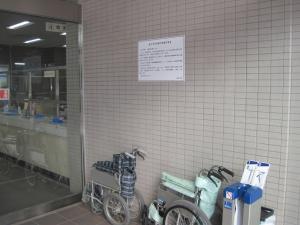 市役所の玄関に車いすや傘のビニール袋が置いてあるところの壁に「非核平和都市宣言」パネルが設置されている写真