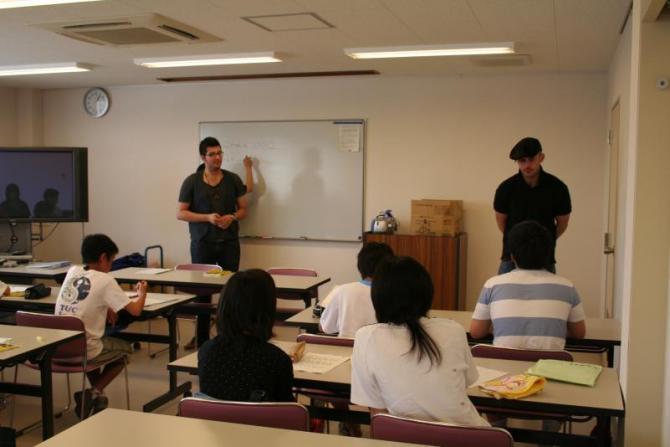 教室の前方に立っている2人の留学生によるフランス語研修を受けている生徒たちの写真