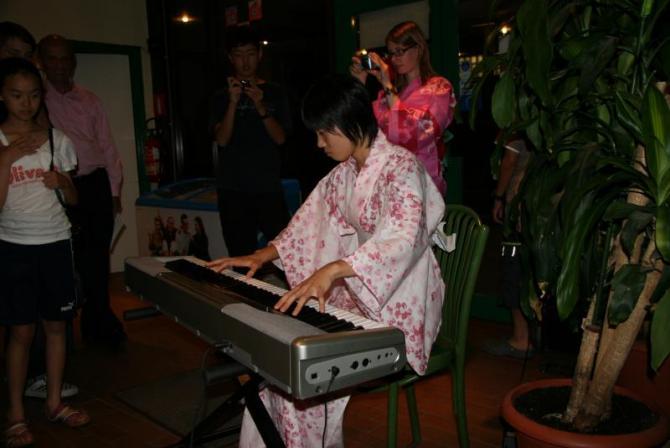 白地にピンク色の模様が入った浴衣を着てピアノを披露している女子生徒の写真