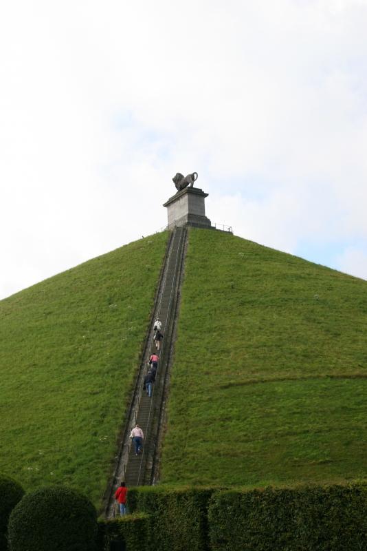 緑色の芝生の丘に頂上へ続く階段がある、ライオン像の丘の写真