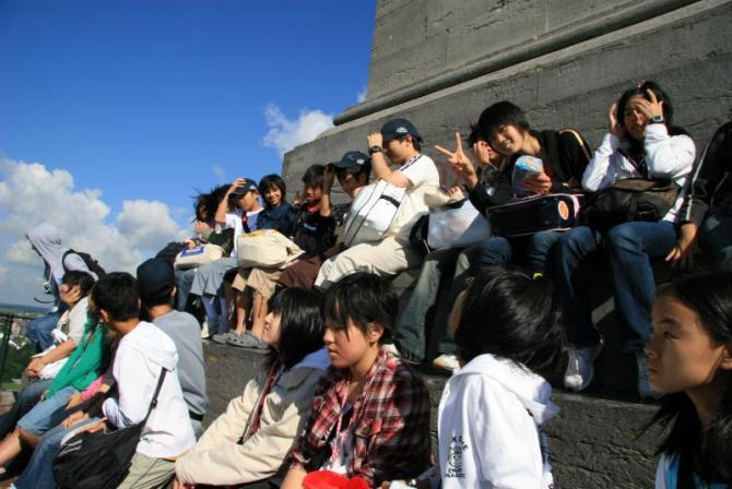 ライオン像の丘の上で石段に腰かけている生徒たちの写真