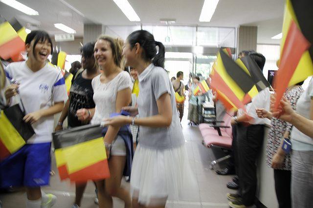 ベルギー国旗の旗をもってワーテルロー市の学生を迎え入れている長久手市の学生の写真