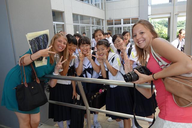 笑顔でピースサインをしている女子中学生とワーテルロー市訪問団の女子学生2人の写真