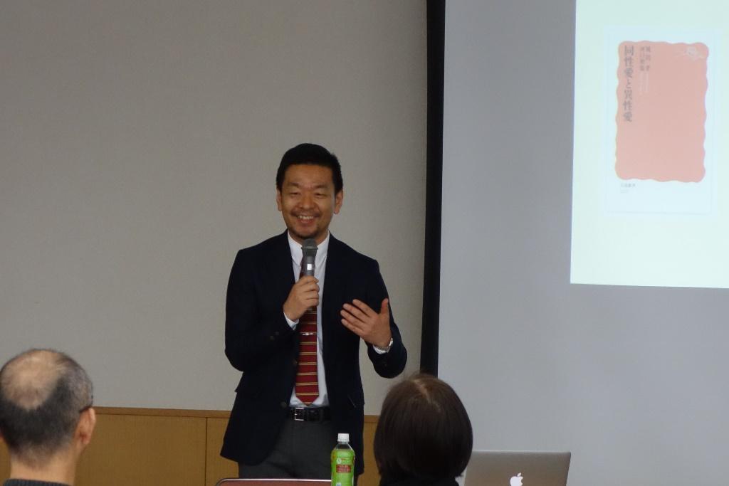 スクリーンに資料を写しマイクを手に持ちながら笑顔で話をしている風間孝先生の写真
