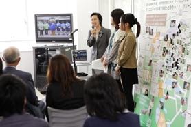 愛知淑徳大学長久手キャンパス コミュニティ・コラボレーションセンターにて、学生などがテレビを使いこれまでの活動事例の紹介を行っている様子の写真
