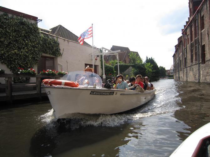 建物の間を流れる川を水上ボートに乗って観光をしている写真
