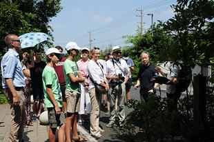 植樹された木の前に、訪問団の方々が集まって、説明を聞いている写真