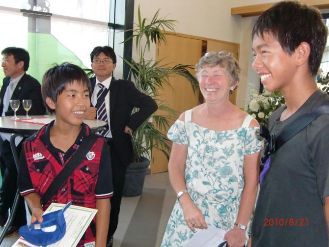 笑いながら立っている2人の男子生徒と1人のホストファミリーの女性の写真