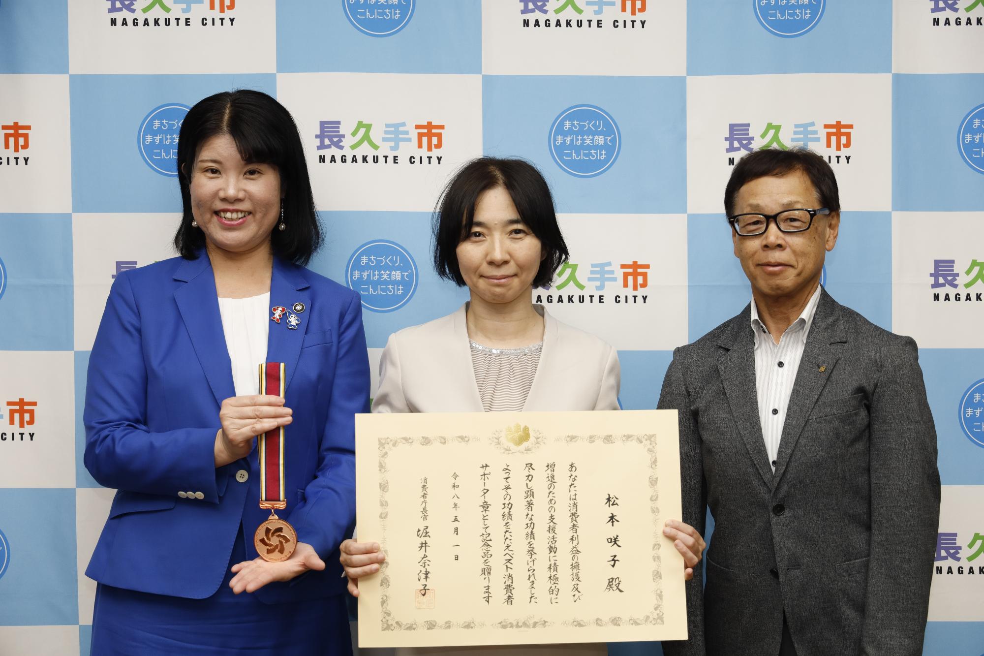 松本咲子教諭と市長、教育長の記念撮影時の写真