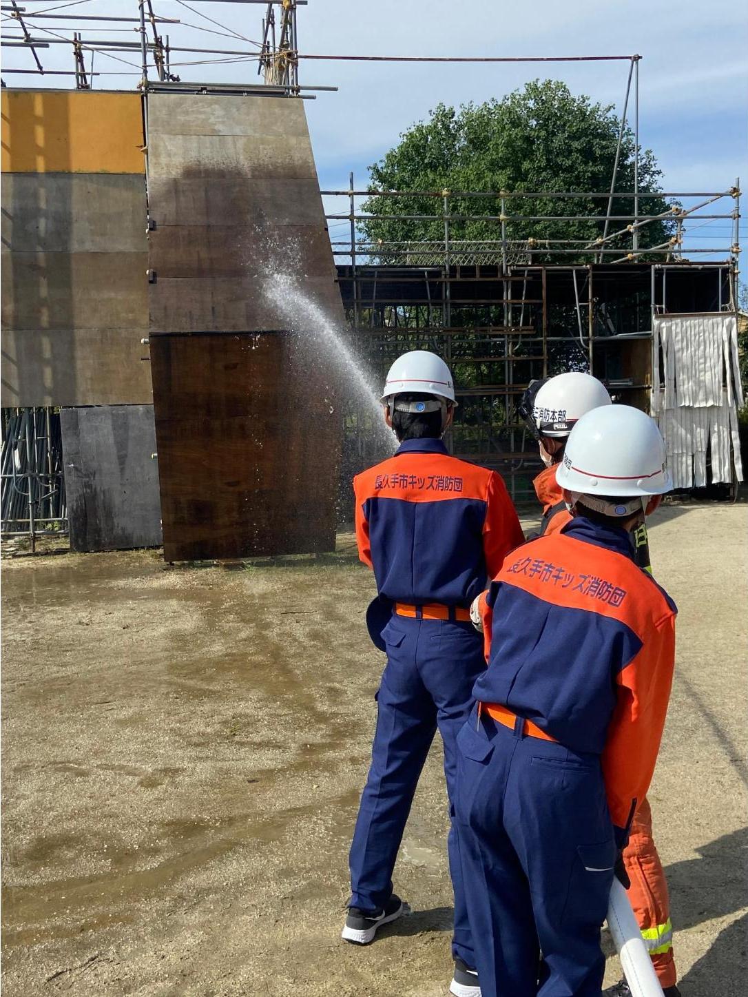 消防職員と放水する長久手市キッズ消防団員の写真