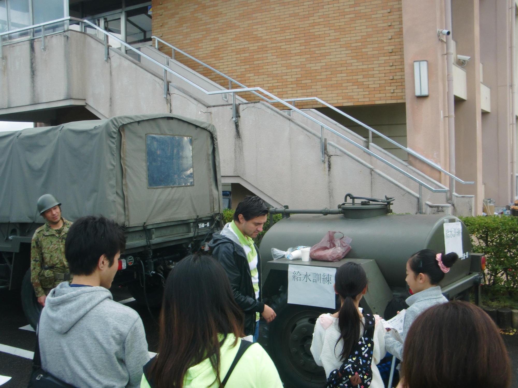 自衛隊の給水車の前に参加者たちが集まっている写真