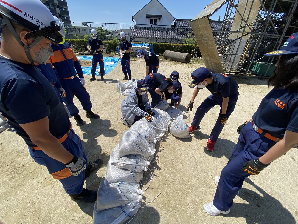 立って並んでいるユニホーム姿のキッズ消防団員たちが敬礼している写真