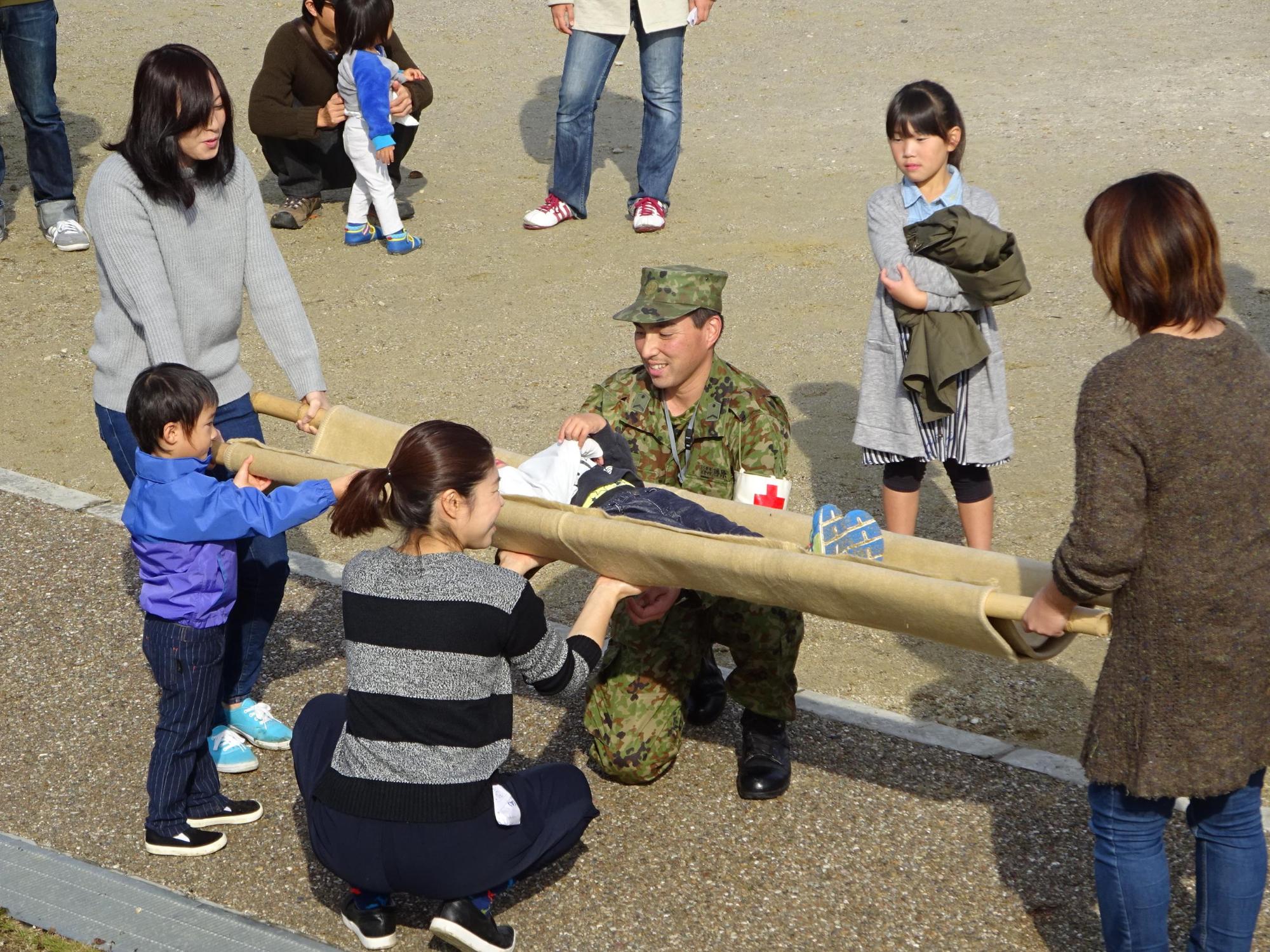 自衛隊の指示の下、毛布と竹を使った担架を使って訓練が行われている写真