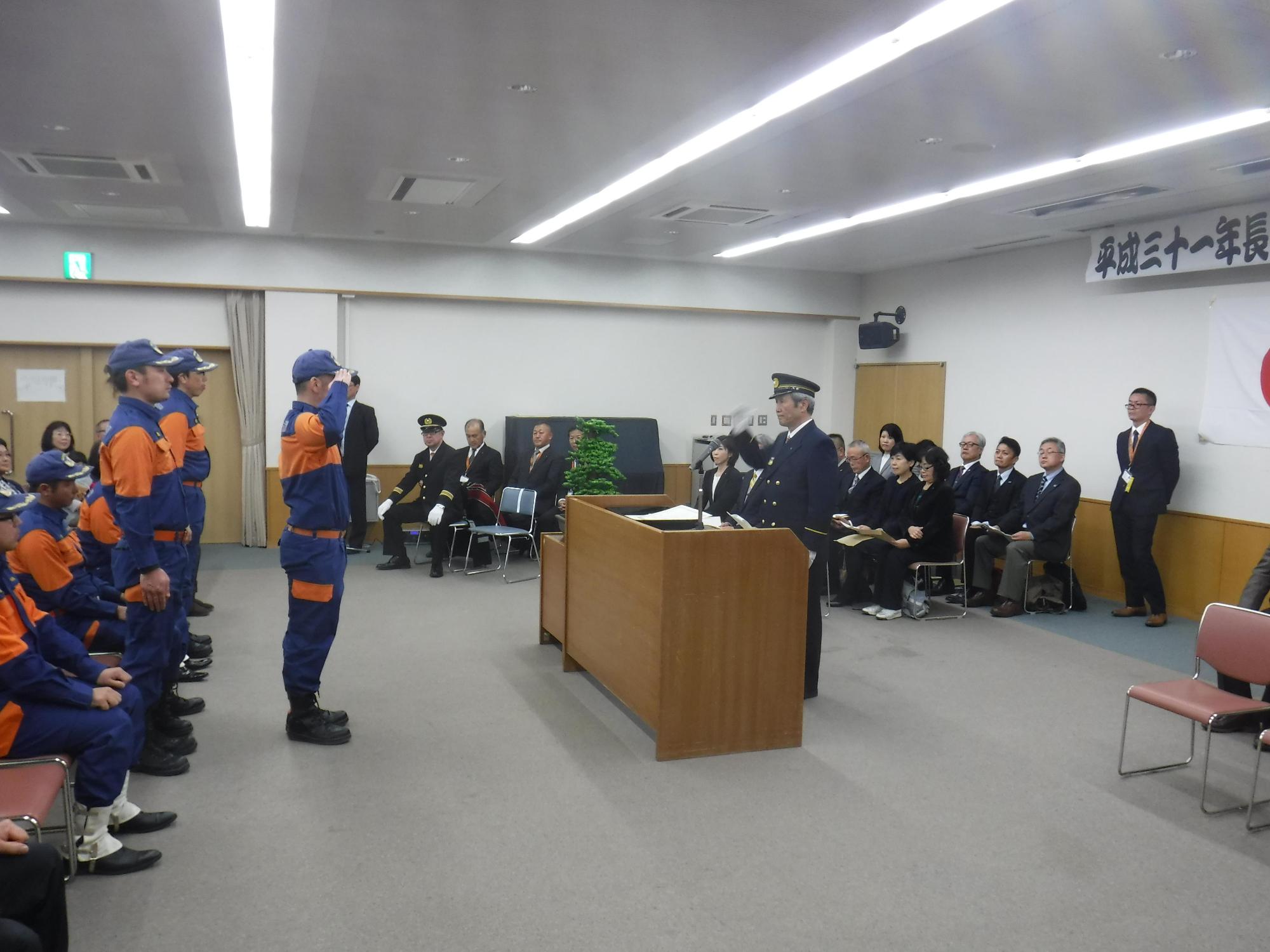 出初式にて消防団員の代表と市長がお互いに敬礼している写真