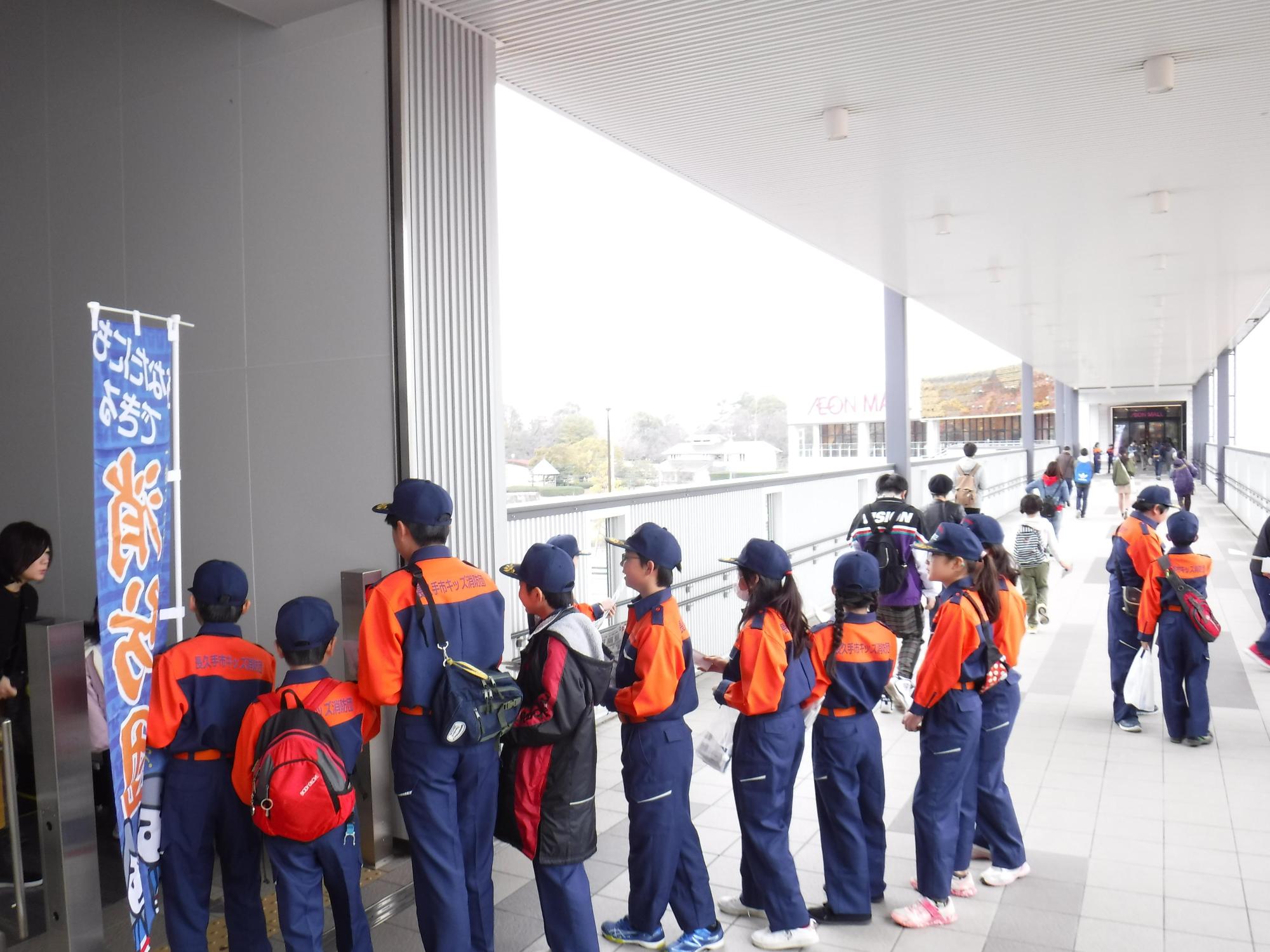 紺色とオレンジ色の消防隊員の服装をした子供たちが1列に並んでいる写真