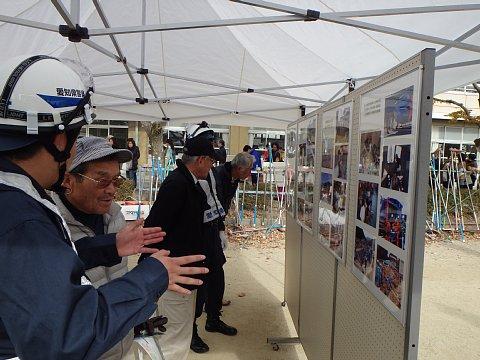 校庭に設置されたテントの下に、愛知警察署によるパネルの展示を男性の参加者たちが熱心に見ている写真