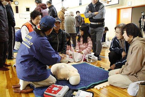 （長小）応急救護ボランティアの指導によるAEDを用いた心肺蘇生訓練ブースで話を聞いている参加者たちの写真