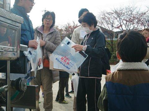 （西小）愛知中部水道企業団による給水訓練にて給水袋を持って並ぶ参加者たちの写真