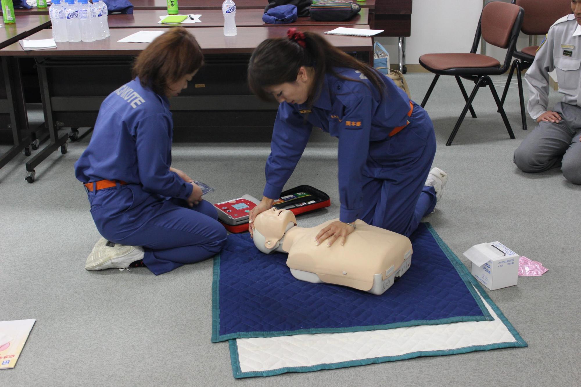 救急講習会で女性消防団員たちが人形を使った心臓マッサージをしている写真