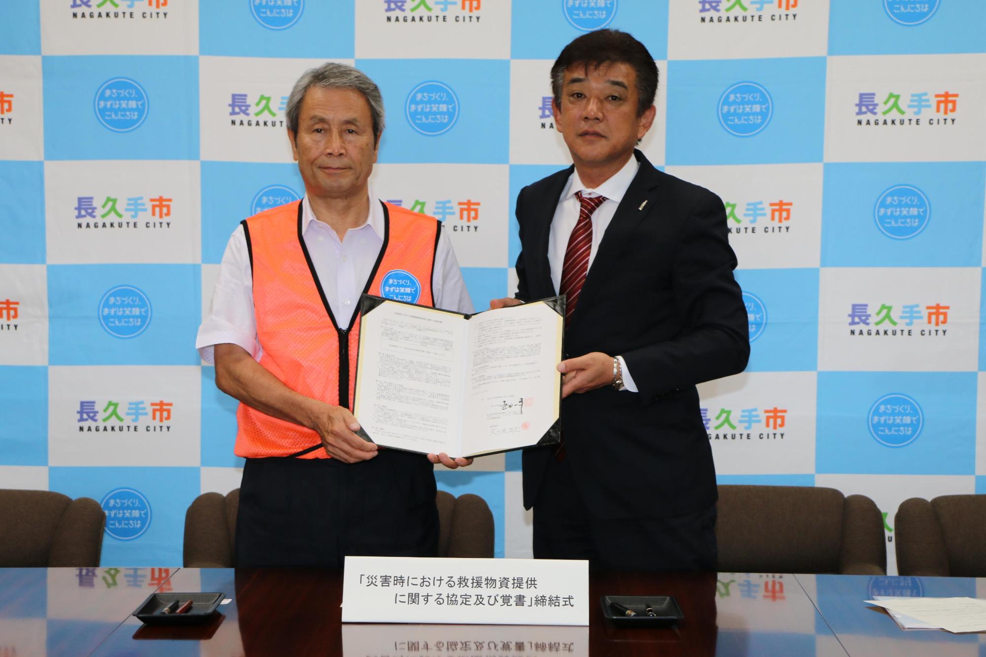 市長とコカ・コーライーストジャパン株式会社の関係者の男性が協定書を二人で持って広げて見せ、並んで写っている写真