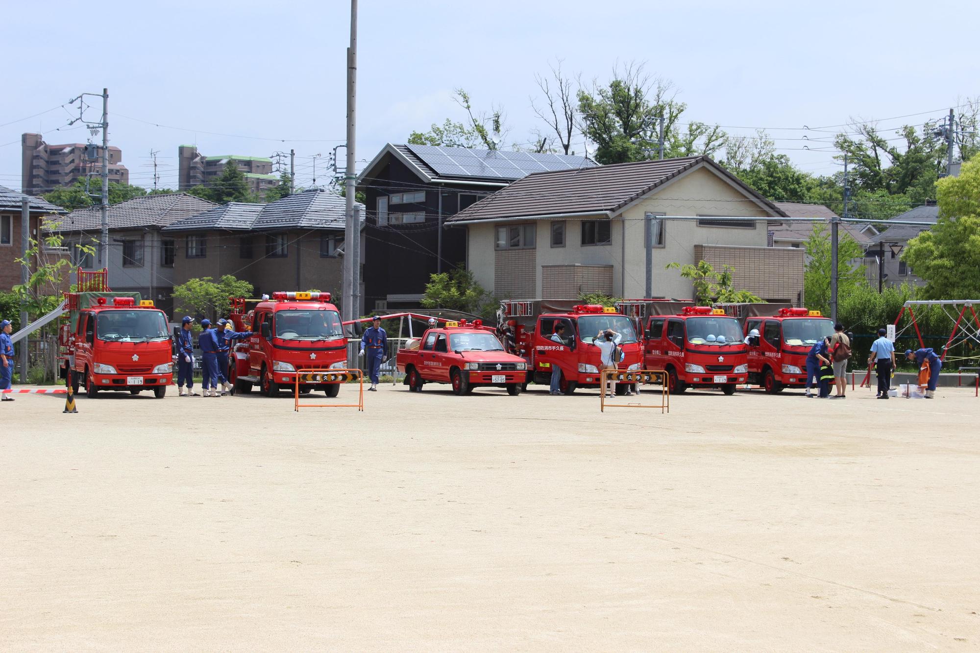 グラウンドに消防車両が6台駐車されている写真