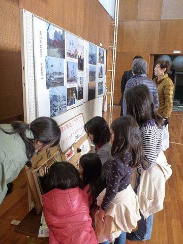 電力復旧の写真を展示しているブースに、女性や女の子の参加者が見学している写真