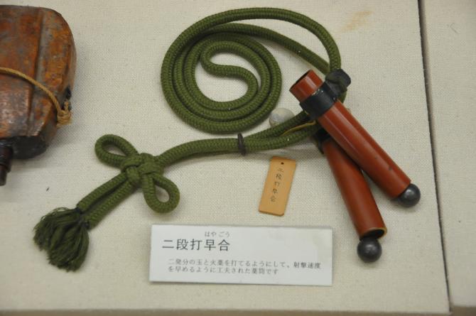 茶色の棒が2本あり棒から緑色の紐が伸びている二段打早合の写真
