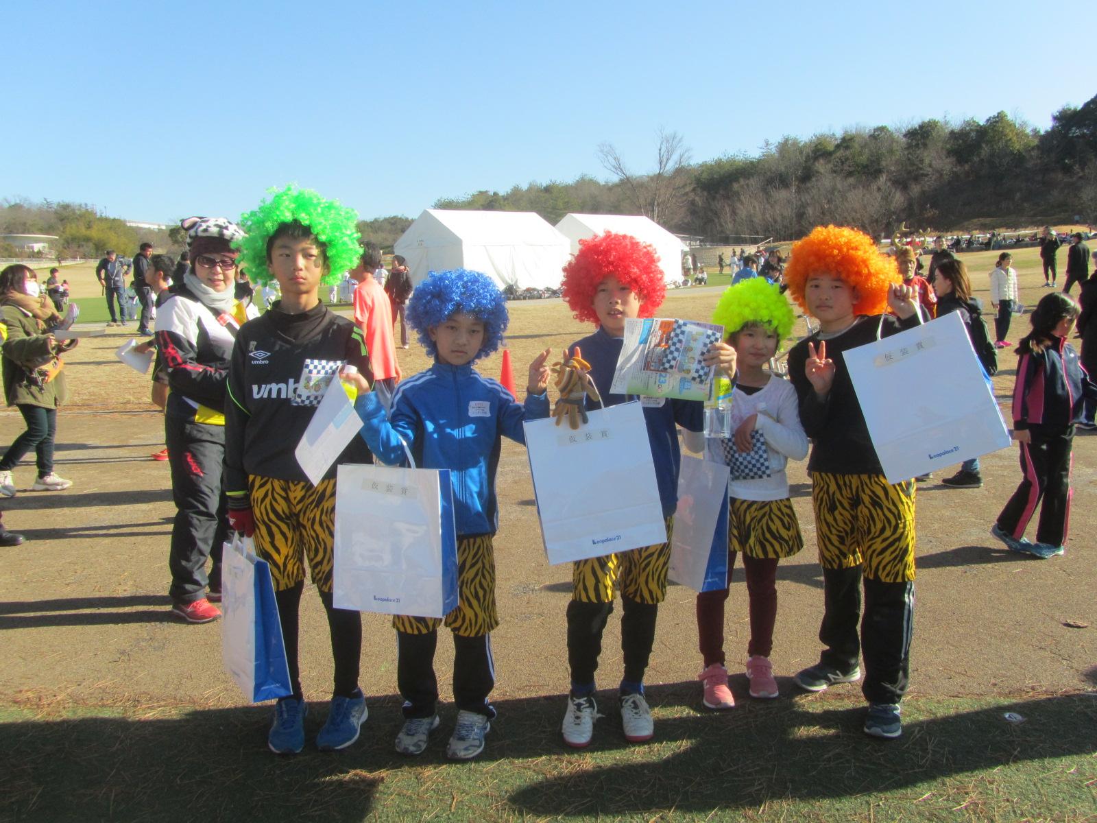 緑、青、赤、黄色、オレンジのパーマがかかったかつらをかぶり虎柄のパンツを履いてオニの仮装をしている5人の子供たちがピースサインをして写っている写真