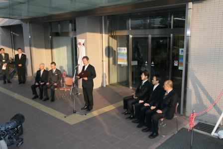 長久手市役所正面玄関前で開市宣言をしている吉田市長と、その両脇の椅子に腰かけている5名の来賓の方々の写真