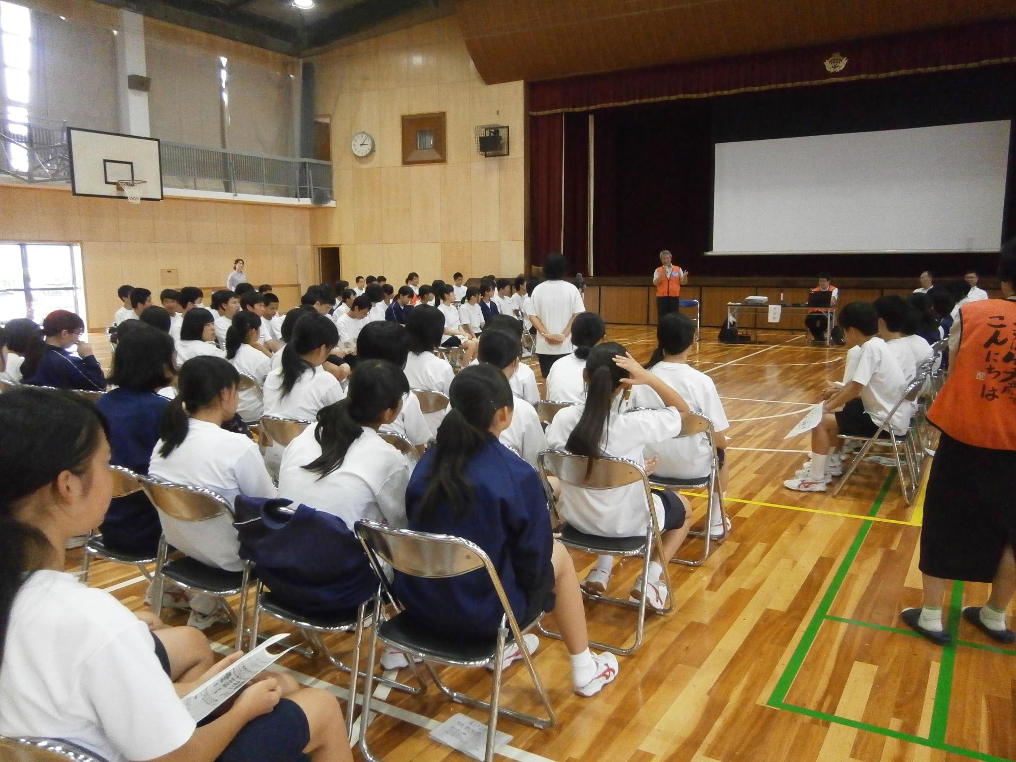 体育館でたくさんの生徒が座りながら市長の話を聞いている写真