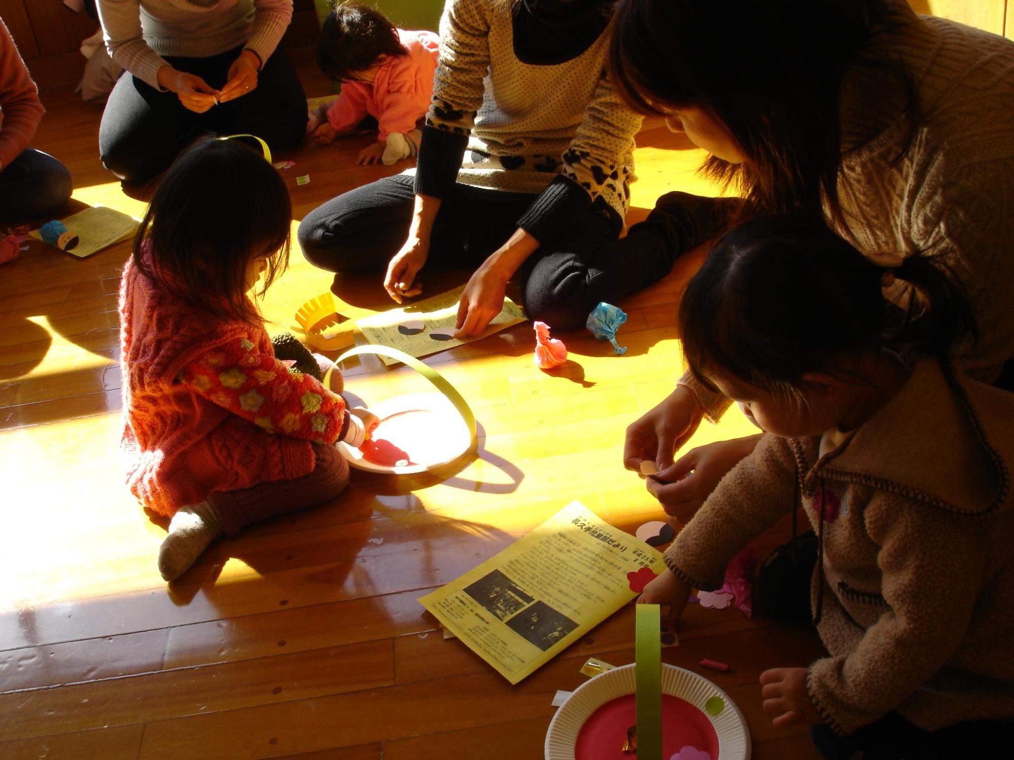 お母さんや子供たちが紙皿などを使って工作している様子の写真