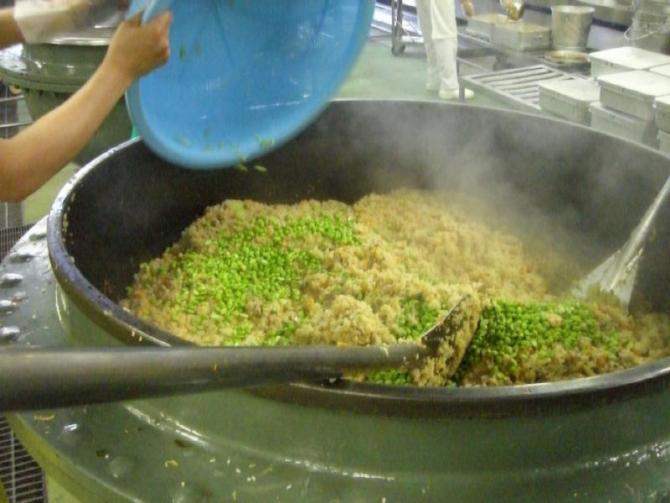 大きな釜で炊いた中華おこわの仕上げに枝豆を投入している写真